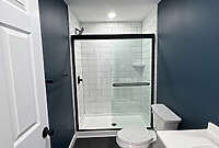 wooden_basement_bathroom remodel_2 bathroom remodel in basement with navy blue walls, black flooring, back hardware and white subway vinyl shower