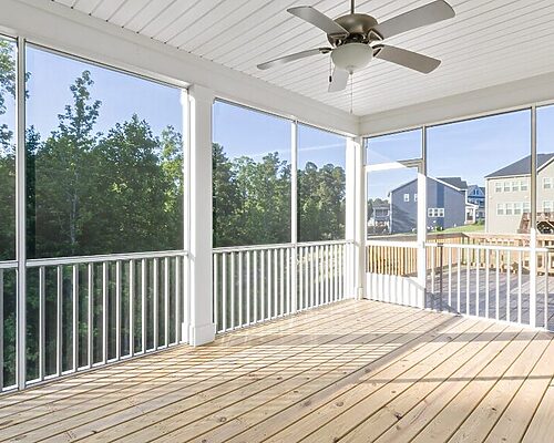 screened in porch with large windows and a ceiling fan. doorway leads to a deck