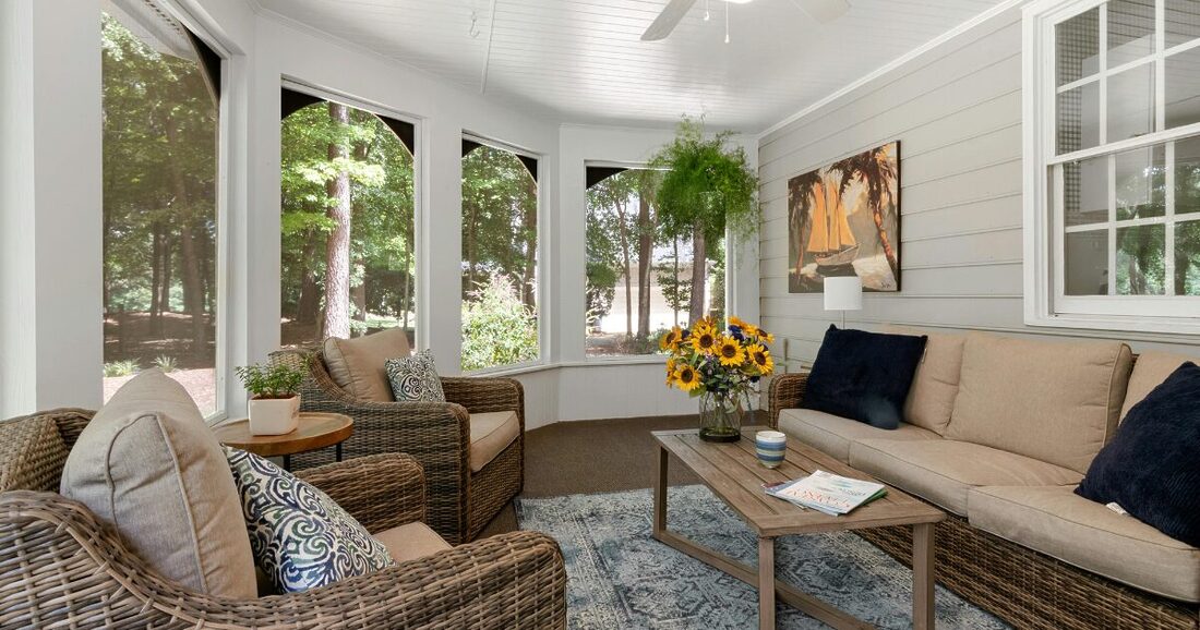 three-season room with large windows, hanging plants and outdoor couch and chair