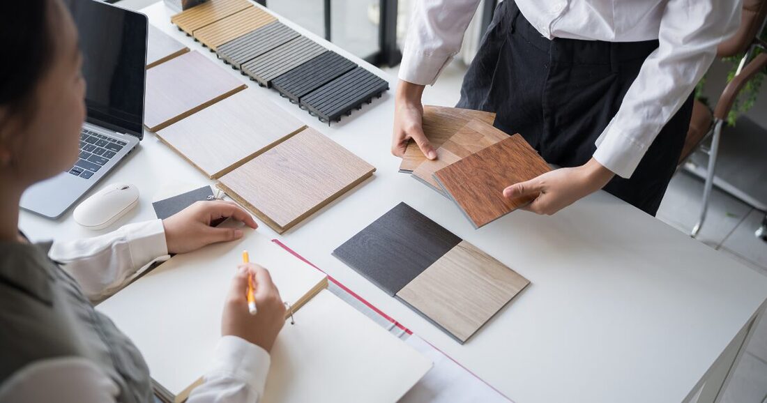 two people looking at LVP flooring samples on top of a white table
