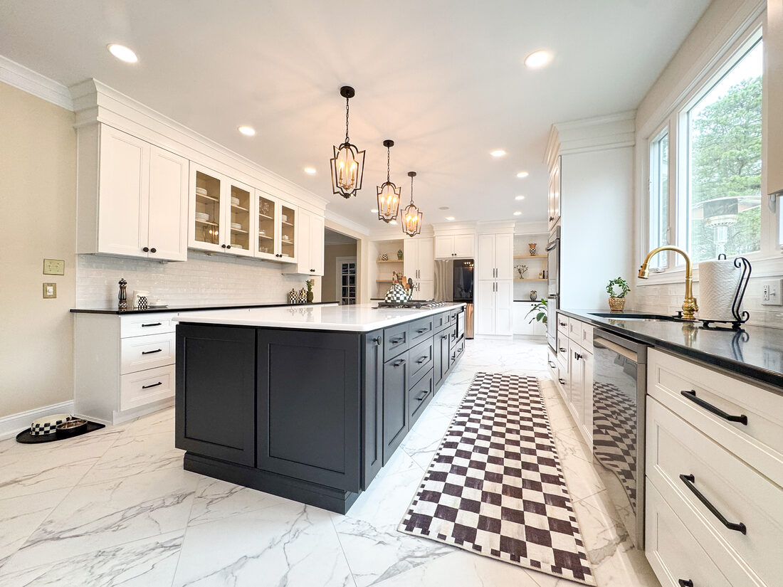 Custom white shaker kitchen cabinets with glass-front upper cabinets, black countertops, white subway tile backsplash, and matte black hardware in a bright modern kitchen remodel.